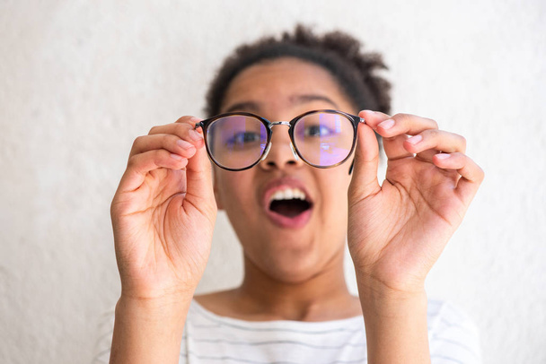 Close up retrato de jovem afro-americana segurando óculos fazendo cara engraçada por parede branca
 - Foto, Imagem