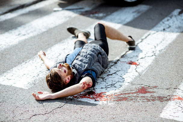 Injured bleeding man on the road - Foto, afbeelding