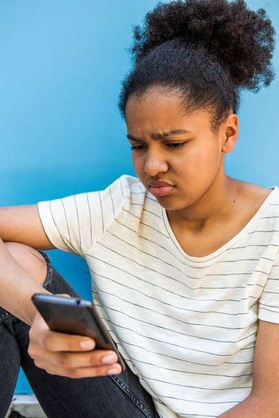 Close up portrait of sad young african american girl looking at cellphone - Foto, Bild