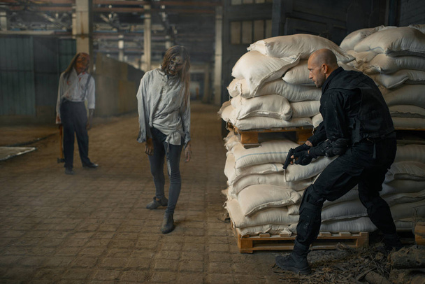 L'homme militaire se cache des zombies dans une usine abandonnée. Horreur en ville, rampements effrayants, apocalypse funeste, monstres diaboliques sanglants
 - Photo, image