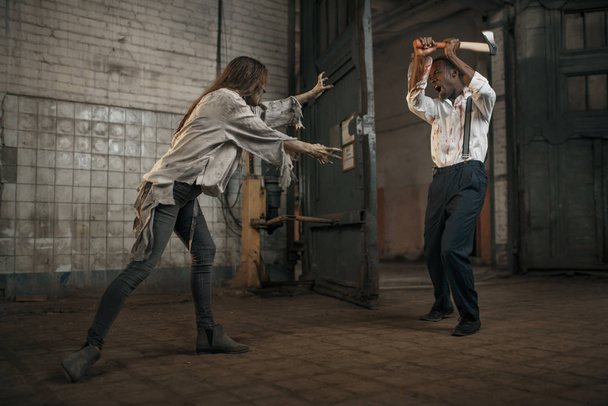 weibliche Zombie kämpft mit verängstigten Mann in verlassenen Fabrik. Horror in der Stadt, gruselige Kriechtiere, Weltuntergangsapokalypse, blutige böse Monster - Foto, Bild