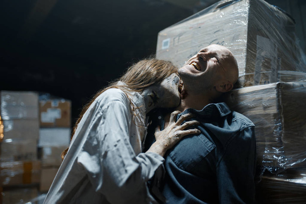 weiblicher Zombie beißt einen Mann in den Hals, Todesfalle, tödliche Verfolgungsjagd. Horror in der Stadt, gruselige Kriechattacke, Weltuntergangsapokalypse, blutiges Monster - Foto, Bild