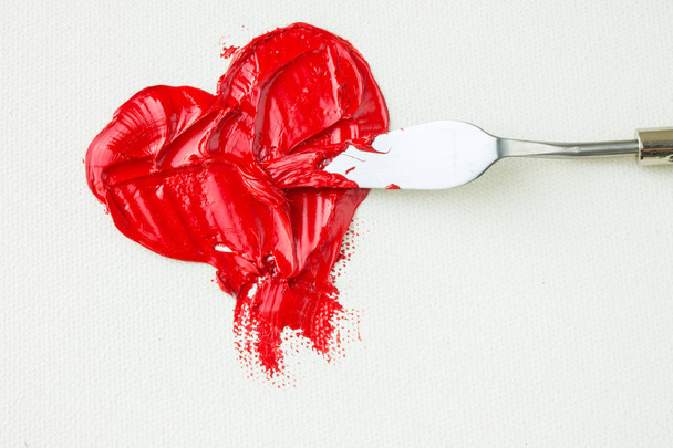 Red heart on white canvas and palette knife - Fotoğraf, Görsel