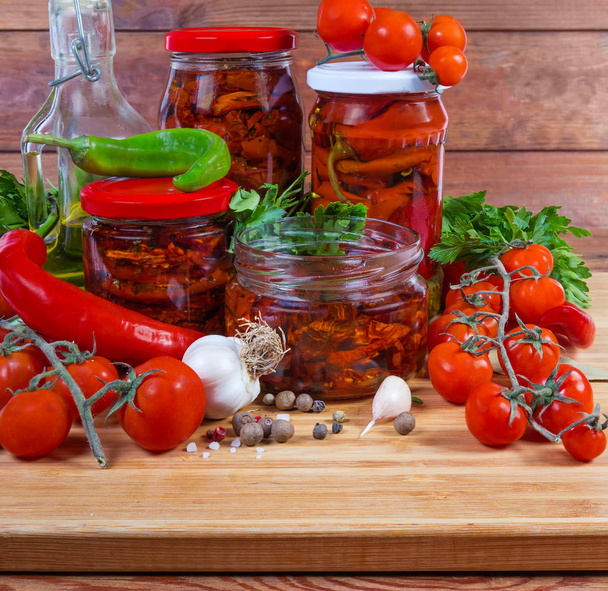 Tomates séchées à l'huile, chili en conserve dans des pots en verre, ingrédients
 - Photo, image