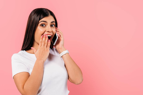 vzrušený hezká brunetka dívka mluví na smartphone izolované na růžové - Fotografie, Obrázek
