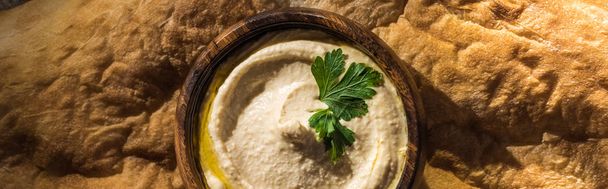 Draufsicht auf köstlichen Hummus in Schüssel auf frisch gebackener Flade, Panoramaaufnahme - Foto, Bild