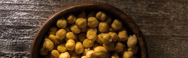 top view of chickpeas in bowl on wooden rustic table, panoramic shot - Foto, afbeelding