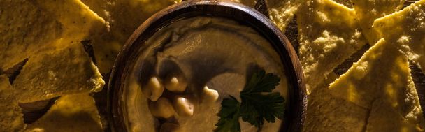 top view of delicious hummus with chickpeas in bowl near nachos, panoramic shot - 写真・画像