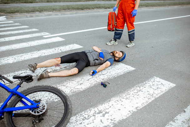 Road accident with injured cyclist and medic going to help - Photo, Image
