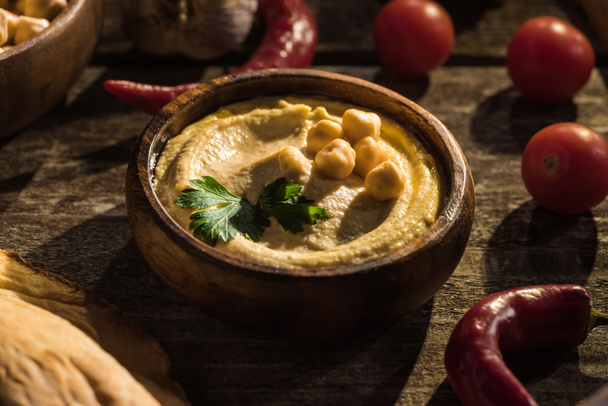 delicious hummus, chickpeas, chili peppers and cherry tomatoes on wooden rustic table - 写真・画像