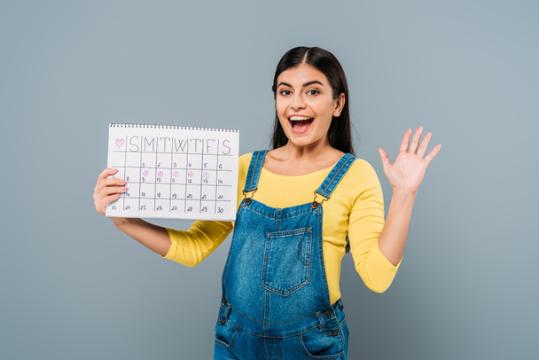 excited pregnant pretty girl holding period calendar isolated on grey - Foto, Imagem