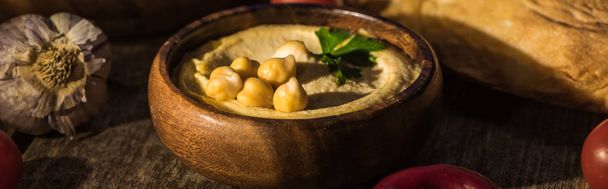 delicious hummus, chickpeas, pita, garlic on wooden rustic table, panoramic shot - Photo, Image