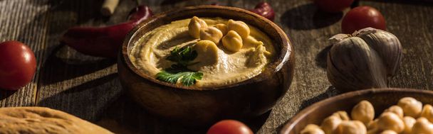 delicious hummus, chickpeas, pita, vegetables and spices on wooden rustic table, panoramic shot - Photo, Image