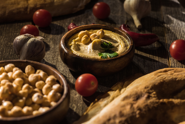 delicioso hummus, garbanzos, pita, verduras y especias en la mesa rústica de madera
 - Foto, imagen