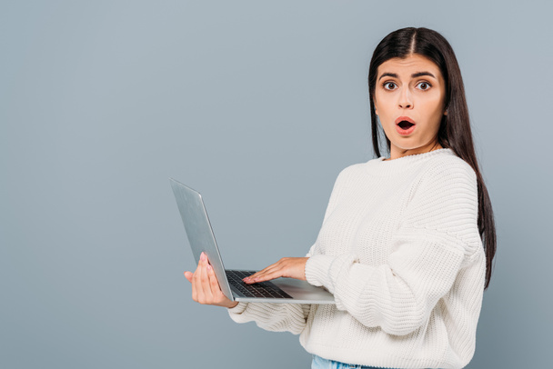 shocked pretty girl in white sweater using laptop isolated on grey - Fotoğraf, Görsel