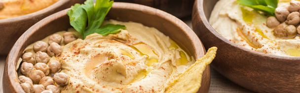 close up view of delicious hummus with chickpeas and nacho in bowls, panoramic shot - Фото, изображение