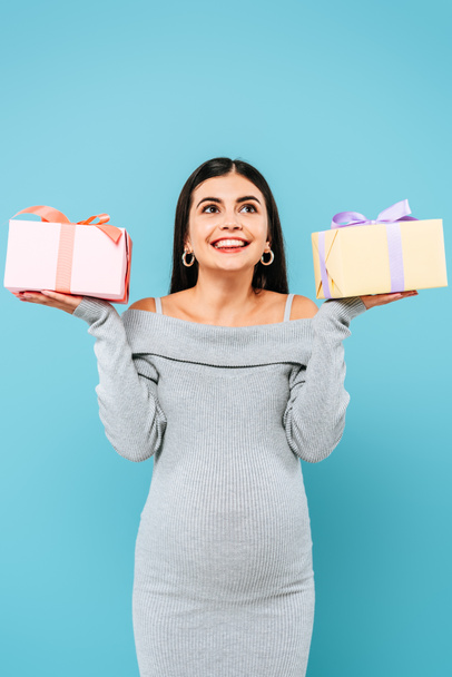 smiling pregnant pretty girl holding presents isolated on blue - Фото, зображення