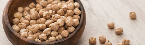 chickpeas scattered from bowl on beige wooden table, panoramic shot - Foto, imagen