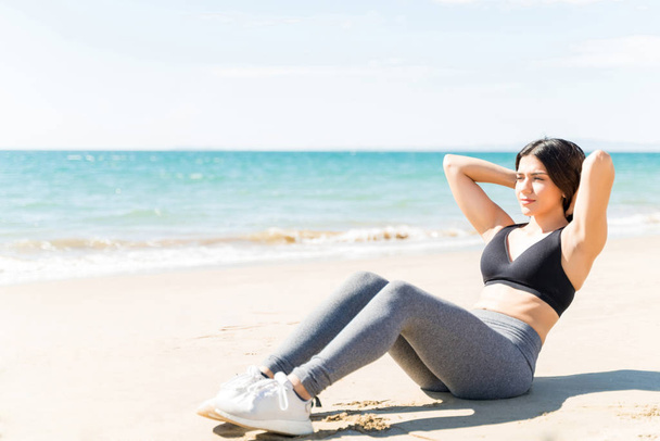 Kobieta w odzieży sportowej chrupie na plaży w słoneczny dzień - Zdjęcie, obraz