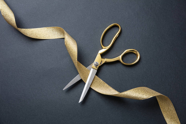 Gran inauguración. Tijeras de oro cortando cinta de satén de oro, fondo negro
 - Foto, imagen