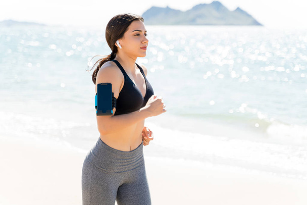 Atrakcyjna kobieta z smartphone jogging na plaży latem - Zdjęcie, obraz