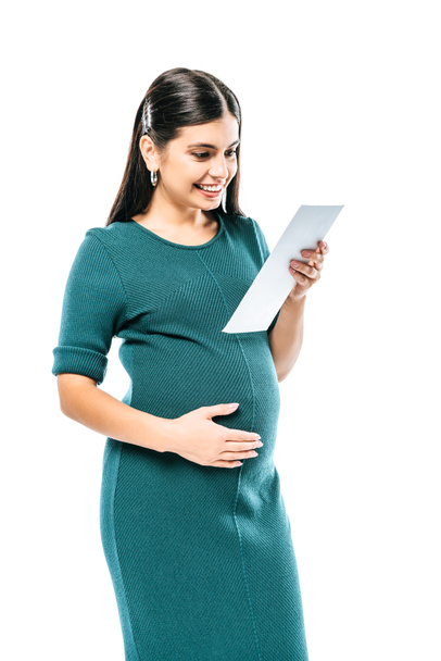 smiling pregnant girl looking at fetal ultrasound images isolated on white - 写真・画像