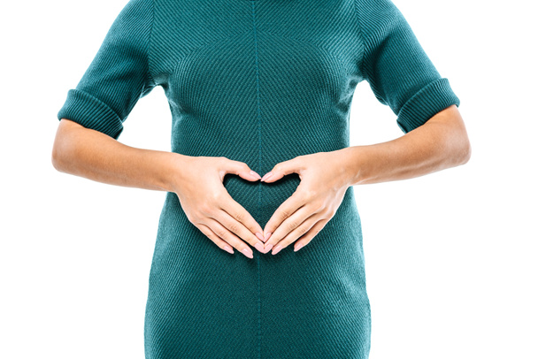 bijgesneden weergave van zwanger meisje tonen hart gebaar op buik geïsoleerd op wit - Foto, afbeelding