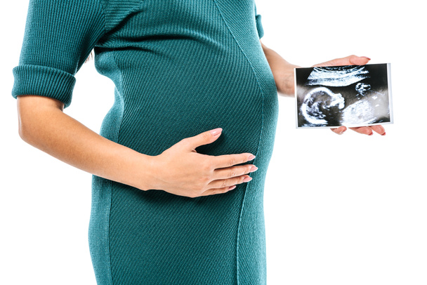 обрізаний вид вагітної дівчини, що тримає ультразвукове зображення плоду ізольовано на білому
 - Фото, зображення
