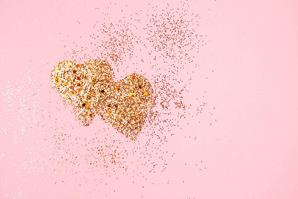 Two golden glitter hearts on a pink background - Foto, imagen