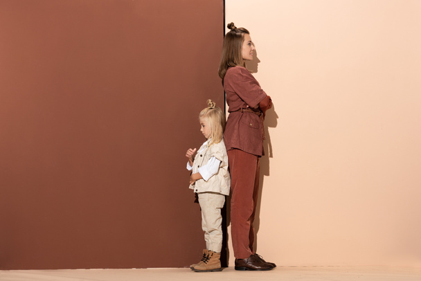 back to back view of daughter and smiling mother on beige and brown background  - 写真・画像