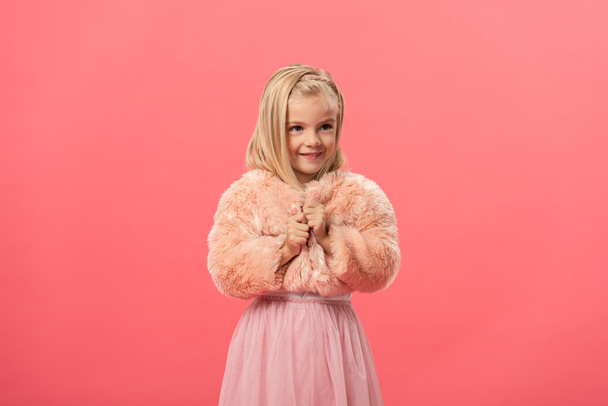 lindo y sonriente niño en abrigo de piel aislado en rosa
 - Foto, imagen