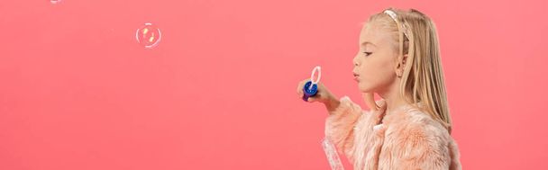 panoramic shot of cute kid blowing soap bubbles isolated on pink - Foto, imagen
