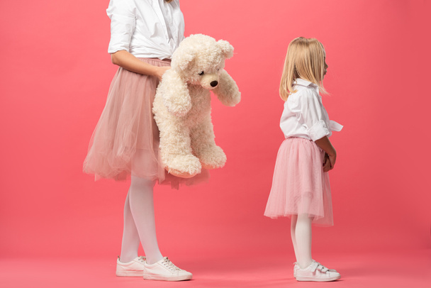 vista ritagliata di madre dando orsacchiotto alla figlia offesa su sfondo rosa
  - Foto, immagini
