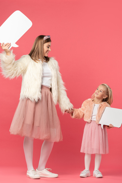 glimlachende dochter en moeder houden toespraak bubbels op roze achtergrond  - Foto, afbeelding