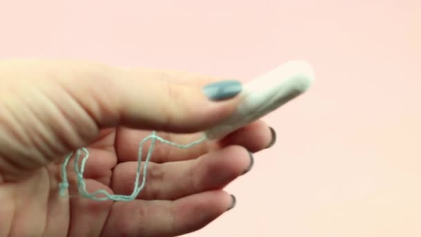 Close up of woman hand holding menstruation cotton tampon on pink background. Feminine hygiene product. - Footage, Video