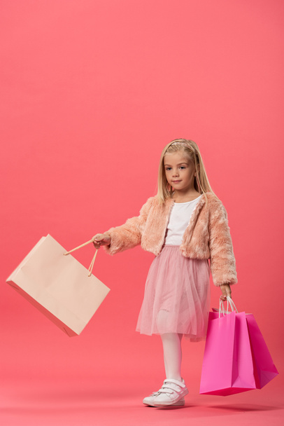 cute kid holding shopping bags on pink background with copy space   - 写真・画像