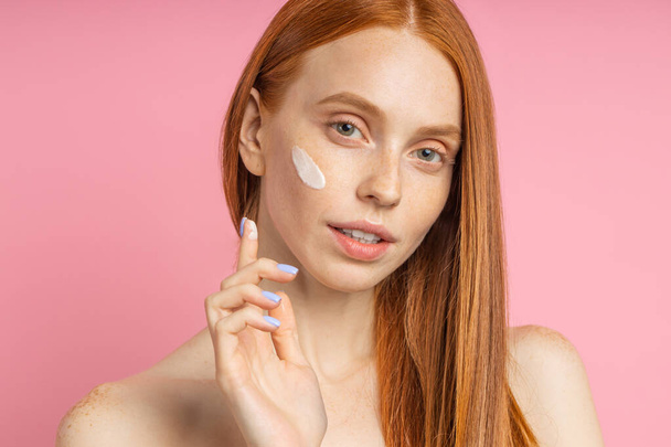 Beautiful young ginger woman with cream on face - Fotografie, Obrázek