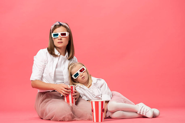 sleepy daughter and mother in 3d glasses with popcorn on pink background  - Foto, afbeelding