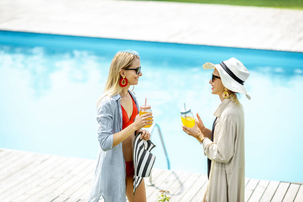 Girlfriends on the swimming pool outdoors - Fotoğraf, Görsel