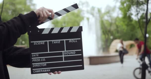 Unrecognizable man claps with clapperboard outdoors. - Footage, Video