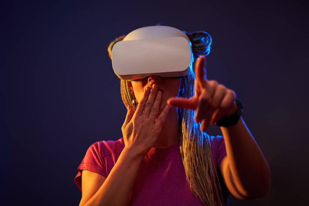 Donna sta usando cuffie realtà virtuale. Neon luce studio ritratto. - Foto, immagini