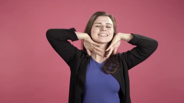 Young woman smiling and dancing in studio against pink background. - Video