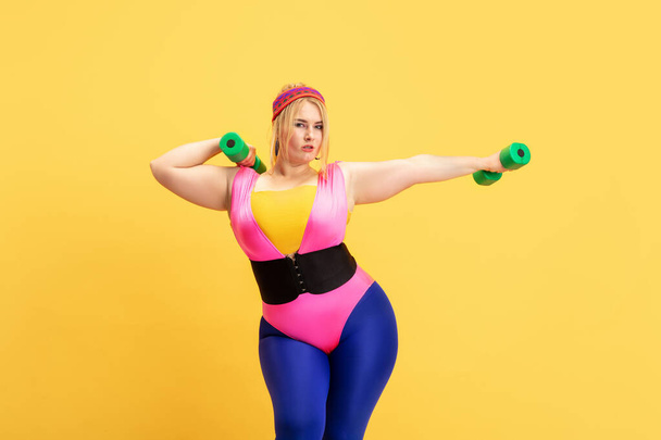 Young caucasian plus size female models training on yellow background - Foto, immagini