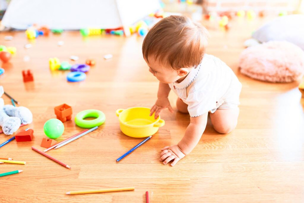 Imádnivaló kisbaba mászkál körbe-körbe egy csomó játékot az óvodában - Fotó, kép