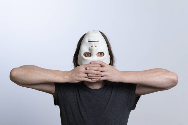 Een man bedekt zijn gezicht met een omgekeerd masker en houdt zijn ellebogen aan de zijkanten met vingers tegen elkaar geklemd.Surrealistisch concept van het zoeken naar de zin van het leven of een andere kijk op de wereld - Foto, afbeelding