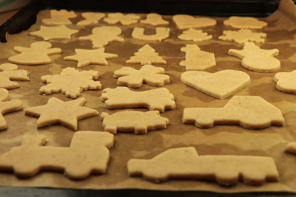 Raw dough for Christmas cookies and cookie cutters shaped glove, Christmas star, snowman, pig, gingerbread man. Concept of winter holidays and work together. Baby Jesus or Santa claus coming soon. - Photo, Image