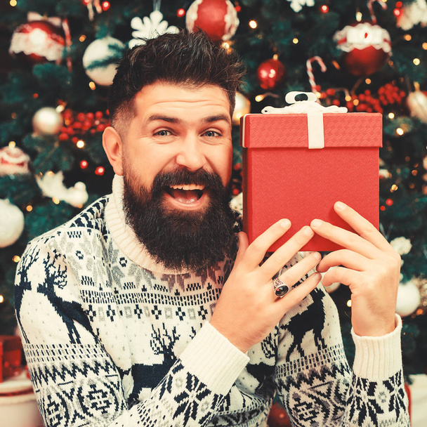髭を生やした男が笑顔でクリスマスプレゼントを持っている。幸せな冬の休日。メリークリスマス - 写真・画像