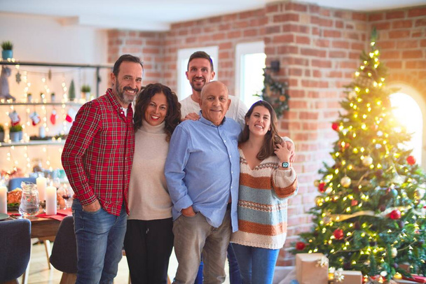 Piękna rodzina uśmiechnięta szczęśliwa i pewna siebie. Stojąc i pozując z drzewem świętując Boże Narodzenie w domu - Zdjęcie, obraz
