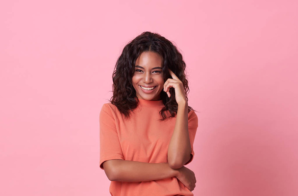 Happy smiling beautiful african woman looking at camera wearing casual orange t-shirt isolated on pink background. - Фото, зображення