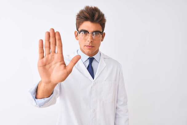 Young handsome sciencist man wearing glasses and coat over isolated white background doing stop sing with palm of the hand. Warning expression with negative and serious gesture on the face. - Photo, Image